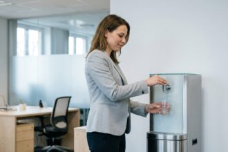 Femme en entreprise utilisant une fontaine à eau de bureau moderne dans un open space professionnel